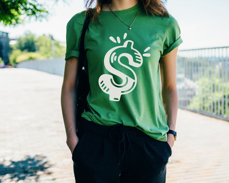 May include: A green t-shirt with a white dollar sign graphic. The dollar sign is stylized with a cartoonish design.
