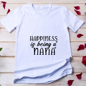 May include: White t-shirt with black text that reads "Happiness is being a NANA".