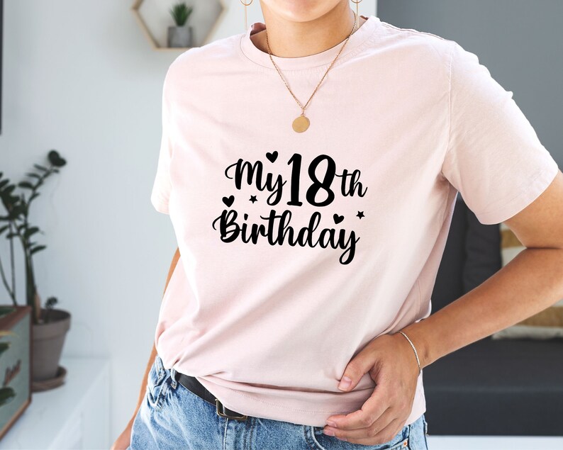 以下が含まれることがあります： ハートと星がついた黒い文字で「My 18th Birthday」と書かれたピンクのTシャツです。