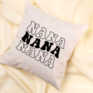 May include: A white throw pillow with the word "NANA" repeated three times in black, stylized text.