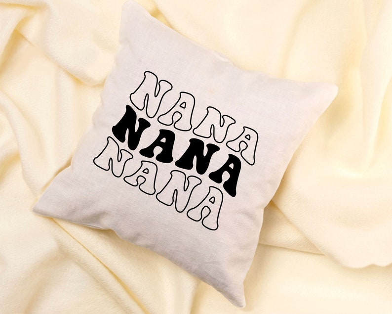 May include: A white throw pillow with the word "NANA" repeated three times in black, stylized text.