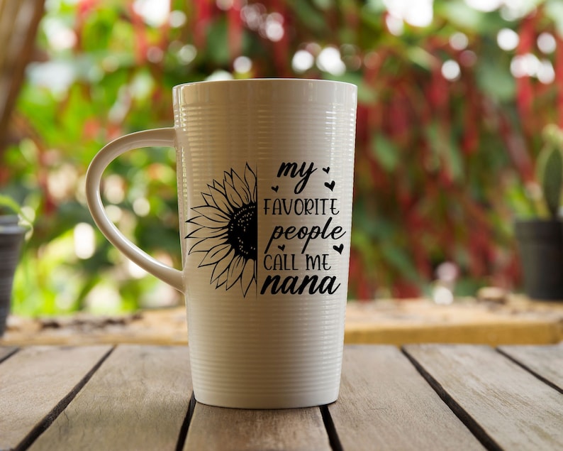 May include: White ceramic mug with a black sunflower design and the text "my favorite people call me nana".