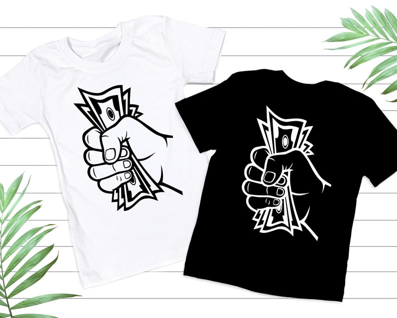 May include: Two t-shirts with a graphic of a hand holding a stack of money. The graphic is in black and white. The t-shirts are one white and one black.