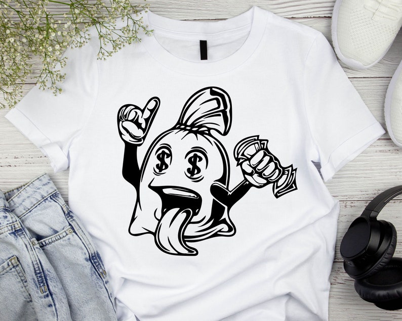 May include: A white t-shirt with a black and white illustration of a money bag with dollar signs for eyes, a tongue sticking out, and a hand holding money. The money bag is wearing a hat.