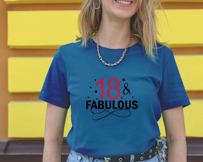 以下が含まれることがあります： 黒と赤の文字で「18 & FABULOUS」と書かれた青いTシャツ。数字の18は赤で、残りの文字は黒です。数字の18の周りに小さな星があります。
