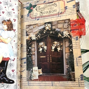 May include: Open journal with a Christmas theme. The right page features a photograph of a decorated doorway with the text "Compliments of the Season." The left page has a printed illustration of a girl in a dress and boots. The journal is trimmed with gold fabric.