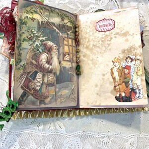 May include: Open journal with vintage Christmas illustrations. One page shows Santa Claus, the other has children and the word "Blessed" in a red label. The journal has a gold fringe and a beaded spine.