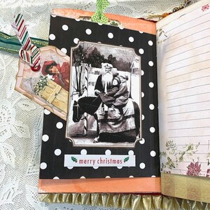 May include: Open journal with a black polka dot cover featuring a vintage image of Santa Claus and a child. The image is framed with a white border and the words "merry christmas" are below. A decorative tag and ribbon are attached.