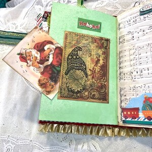 May include: A handmade Christmas journal with a green cover and a decorative gnome image. The journal features a Santa Claus card and the text "Hohoho!" on the cover. The pages have musical notes and a train illustration.