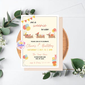 Op de afbeelding: Een rechthoekige verjaardagsuitnodiging met een crèmekleurige achtergrond en drie getekende teckels met feesthoedjes. De tekst luidt: she's a weenie bit older! PLEASE JOIN US TO CELEBRATE Olivia's 4th Birthday SATURDAY | OCT. 12 | 2PM.
