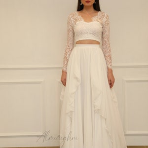 May include: A white crop top with long lace sleeves and a white flowing skirt with ruffles.