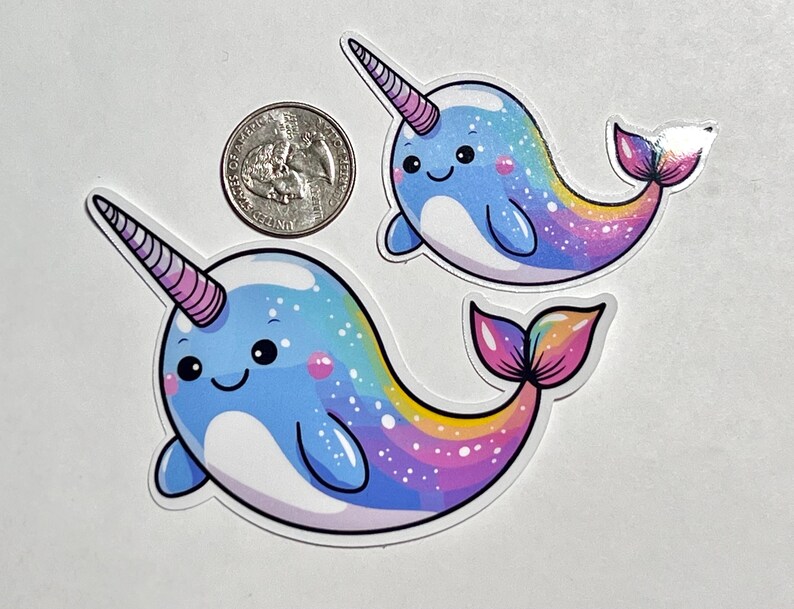 May include: Two cartoon narwhal stickers with rainbow tails and a blue and white body. The narwhals have a pink and white horn and a cute smiling face.