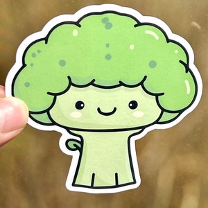 May include: A green cartoon broccoli with a smiling face and a small stem. The broccoli is drawn in a simple, childlike style.