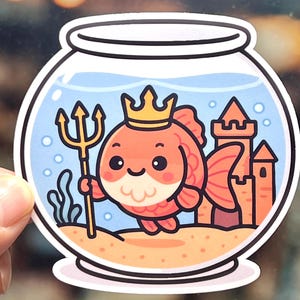 Kawaii goldfish sticker dressed as Poseidon with a crown and a golden trident. A waterproof, laminated vinyl decal shown on an aquarium stand or a laptop, perfect for mythology fans and fish owners
