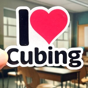 May include: A white sticker with black text that says "I love cubing" and a red heart.