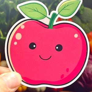 May include: A red apple sticker with a white outline and a happy face. The apple has two green leaves on top.