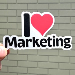 May include: A white sticker with a black "I" and a red heart, followed by the word "Marketing" in black.