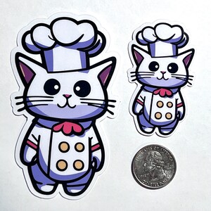 May include: Two cartoon chef cat stickers. The larger sticker is white with a purple body and a pink bow. The smaller sticker is white with a purple body and a red bow. Both stickers have a white chef hat and a yellow button design.