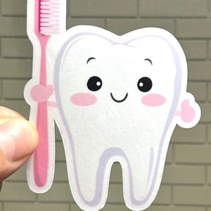May include: A white cartoon tooth with a pink toothbrush. The tooth has a happy face with big eyes and rosy cheeks. The toothbrush is pink with white bristles.