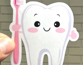 May include: A white cartoon tooth with a pink toothbrush. The tooth has a happy face with big eyes and rosy cheeks. The toothbrush is pink with white bristles.