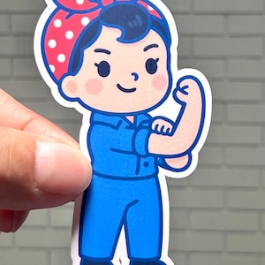 An iconic Rosie the Riveter sticker designed in a charming kawaii style, flexing her arm and wearing her classic red and white polka dot bandana. This premium vinyl decal is shown in small sizes on a laptop lid and in a large 5-inch size on a workshop toolbox to highlight its rugged durability.