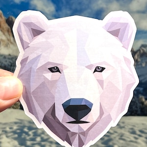May include: A white polar bear head sticker with a geometric design. The bear has a black nose and small, dark eyes.