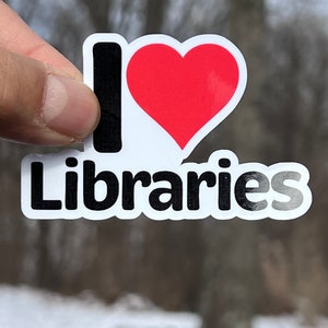 May include: A white sticker with black text that reads "I love Libraries" and a red heart.