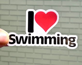 May include: A white sticker with the text "I love Swimming" in black lettering. A red heart is between the "I" and the word "Swimming".