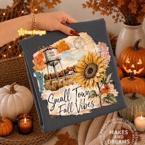May include: A dark gray fabric featuring a graphic print of a water tower, a large yellow sunflower, and vintage paper textures. The text reads Small Town Fall Vibes in a black script font. The design includes a circular postmark stamp.