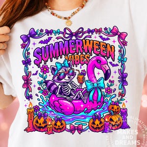 May include: White t-shirt with a colorful graphic featuring a raccoon skeleton wearing sunglasses and a bow, floating on a pink flamingo pool float. The design includes the text "Summerween Vibes" and Halloween-themed elements.