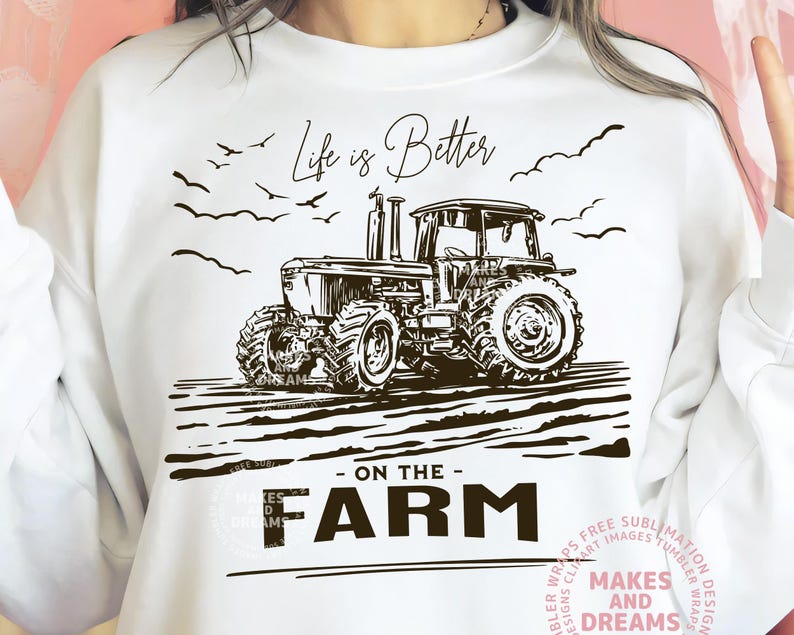 May include: White sweatshirt with a black and white tractor graphic. The design includes the text "Life is Better - ON THE - FARM" with birds and a field illustration. The sweatshirt is a casual, comfortable style.