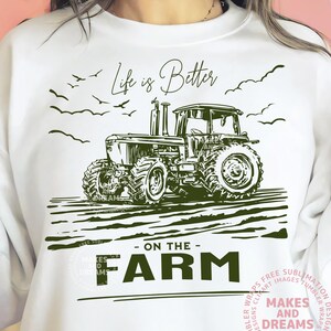 May include: White sweatshirt with a green tractor graphic and the text "Life is Better - On The Farm." The design includes birds and a field, perfect for farm enthusiasts.