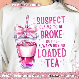 May include: A white sweatshirt with a pink graphic design featuring a pink bow, a pink and white cup of tea, and the text "SUSPECT CLAIMS TO BE BROKE BUT IS ALWAYS BUYING LOADED TEA".