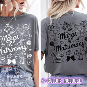 May include: Gray t-shirt with the text "Margs & Matrimony" and various wedding-themed graphics, including cocktail glasses, rings, and bells. The shirt has a relaxed fit and short sleeves. The design is in white and black.