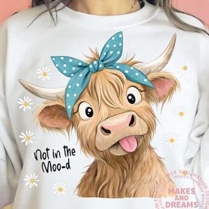 May include: White sweatshirt featuring a cartoon cow with a blue polka dot bow, sticking out its tongue. The text "Not in the Moo-d" is below the cow. Daisy flowers are scattered around the cow.