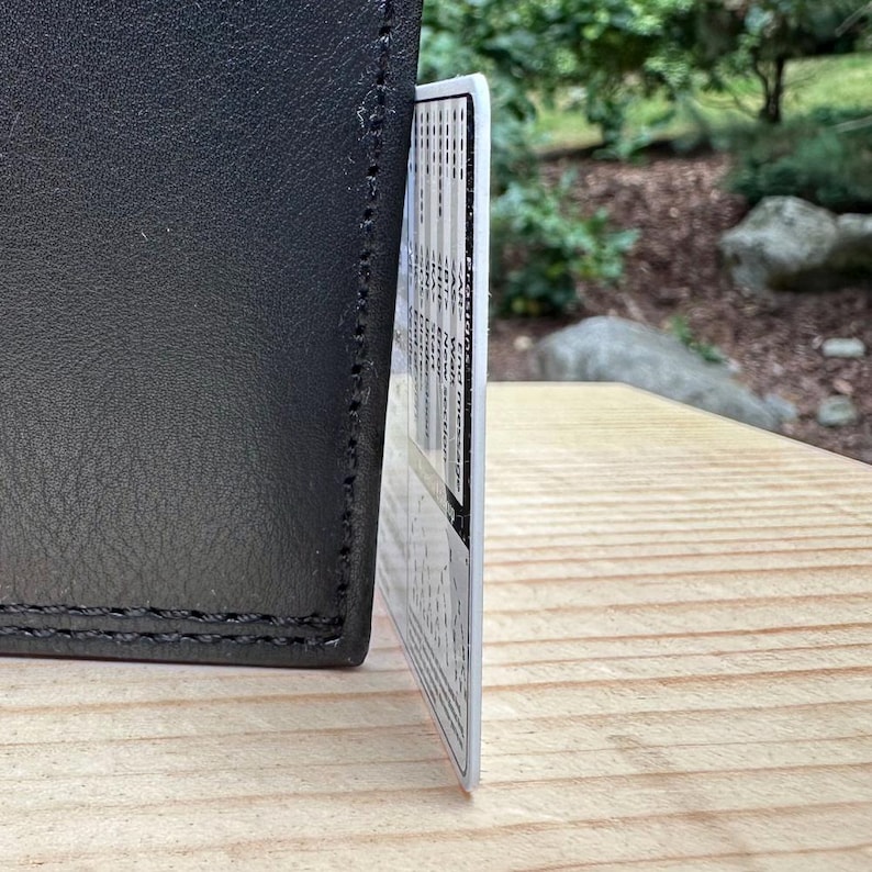 Plastic card leaning against a wallet to show the thickness of the card's plastic.