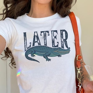 Woman wearing white "Later Gator" Vintage 90s Y2K Baby Tee.