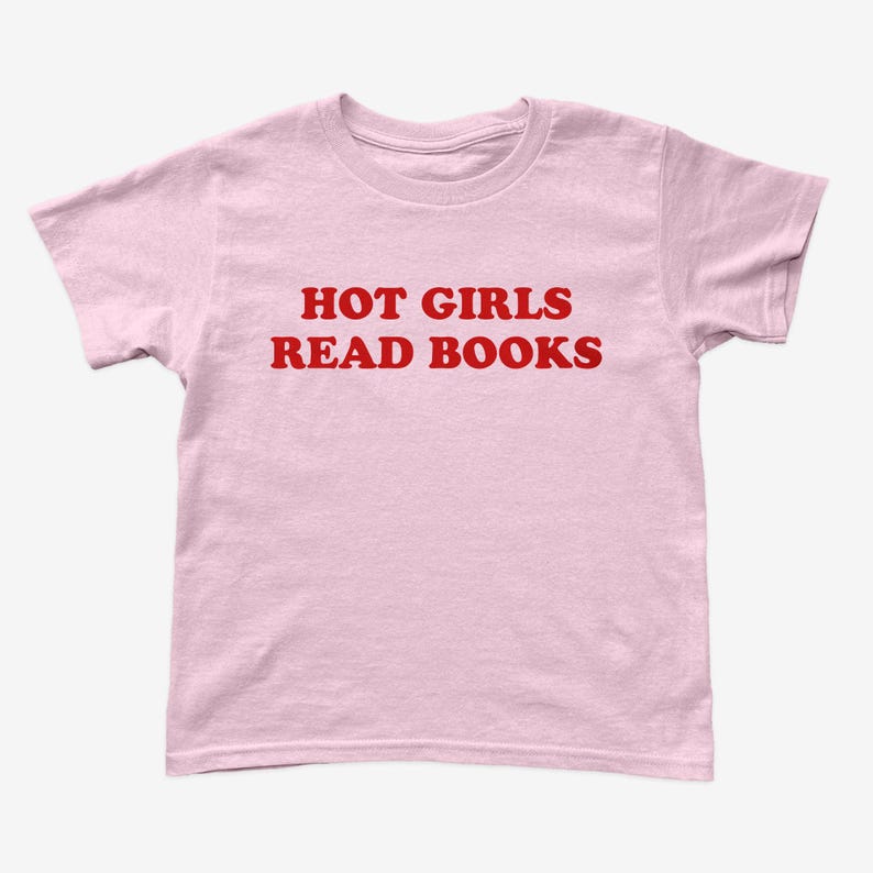 Op de afbeelding: Lichtroze t-shirt met de rode tekst "HOT GIRLS READ BOOKS". Het shirt heeft korte mouwen en een ronde hals.