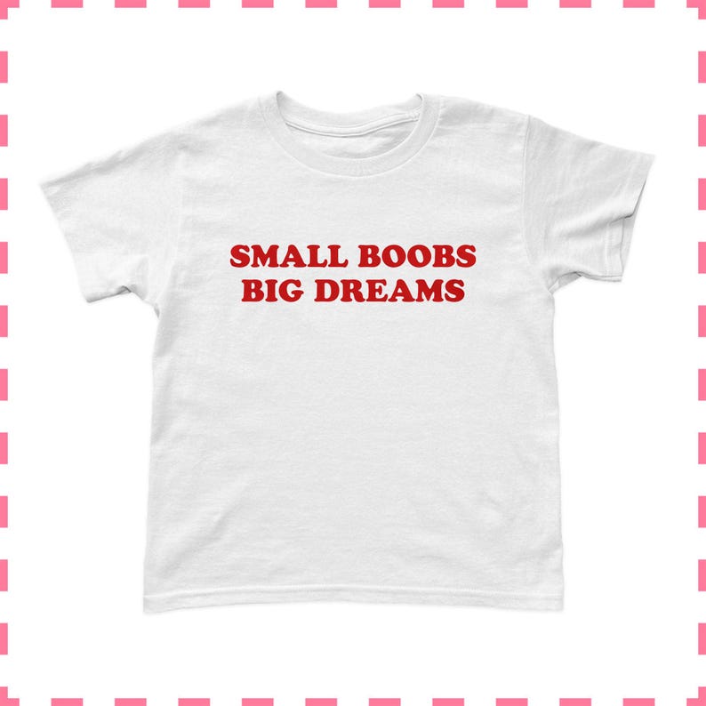 May include: A white t-shirt with the red text "SMALL BOOBS BIG DREAMS" printed across the front. The shirt has short sleeves and a crew neck. The t-shirt is made of a soft, comfortable material.