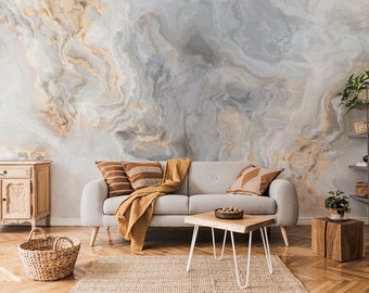 May include: A living room interior with a light gray couch with brown and beige throw pillows and a yellow throw blanket. The wall behind the couch is covered in a gray and beige marble-patterned wallpaper. There is a wooden coffee table in front of the couch and a wooden side table with two drawers to the left of the couch. There is a woven basket on the floor in front of the couch. There is a wooden shelf with various items on it to the right of the couch.