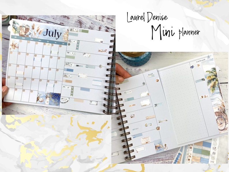 May include: A mini planner with a blue and white cover featuring a beach scene. The planner has a July calendar page and a blank page with a dotted grid. The planner is decorated with stickers and washi tape.