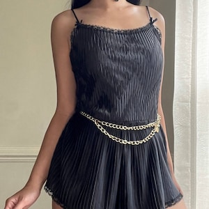Teddy romper in satin black featuring geometric pleating patterns laced lining