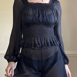 Sheer black organza cropped top featuring pleated fabric with ribbed waistline