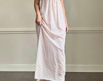 May include: A white maxi dress with a floral print and a lace trim neckline. The dress has a fitted bodice and a flowy skirt.
