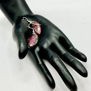 May include: A pair of dangle earrings with pink and green gemstone drops. The earrings are silver and have a simple design.