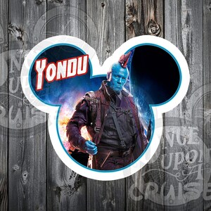 May include: A blue and red Mickey Mouse-shaped sticker with a character from the Guardians of the Galaxy movie. The character is blue with a red mohawk and is holding a weapon. The sticker says "Yondu" in red letters.