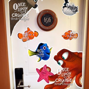 May include: A white door featuring a circular cabin number sign 6516 and multiple character decals including a brown sea lion, a black bird, two orange clownfish, a blue tang fish, a pink starfish, and a red octopus with Once Upon A Cruise text.