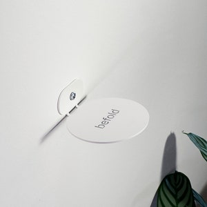 Op de afbeelding: Witte wandplank met het woord "befold" erop gedrukt.