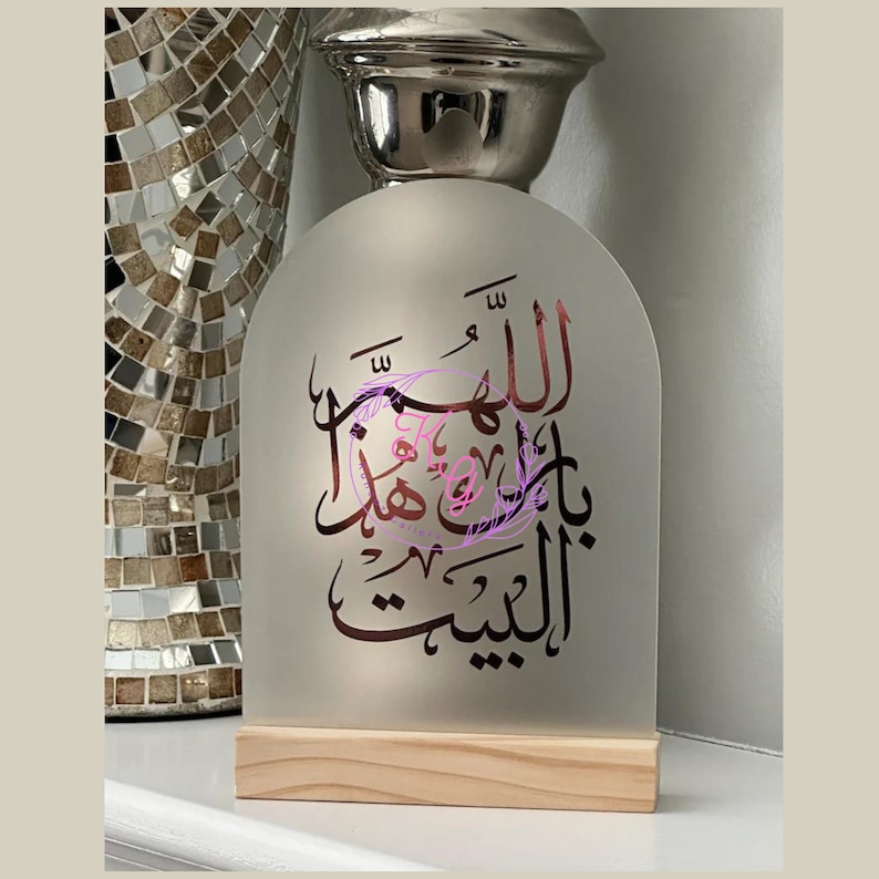 May include: A frosted glass arch with a wooden base, featuring a black Arabic calligraphy design. The calligraphy reads "Allah" in a decorative script.