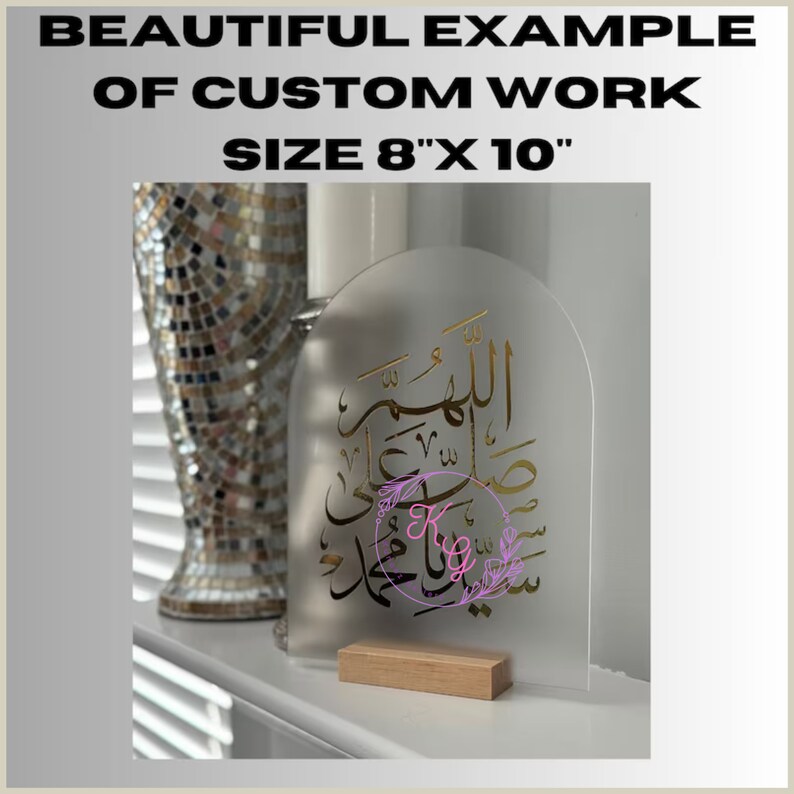 May include: A clear acrylic sign with a gold Arabic calligraphy design on a wooden stand. The sign is 8 inches by 10 inches.